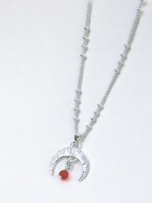 Silver necklace with a moon and red stone pendant on a white background