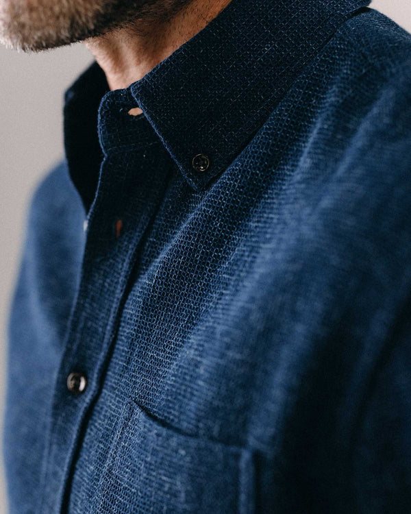Close-up of a person wearing a blue textured shirt with a collar.