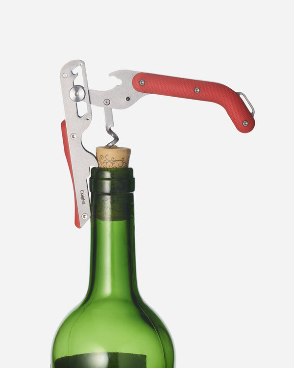 Corkscrew opening a green wine bottle on a white background