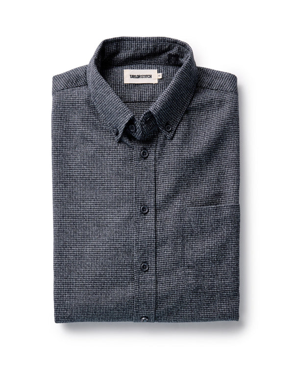 Folded dark navy and gray checkered shirt on a white background