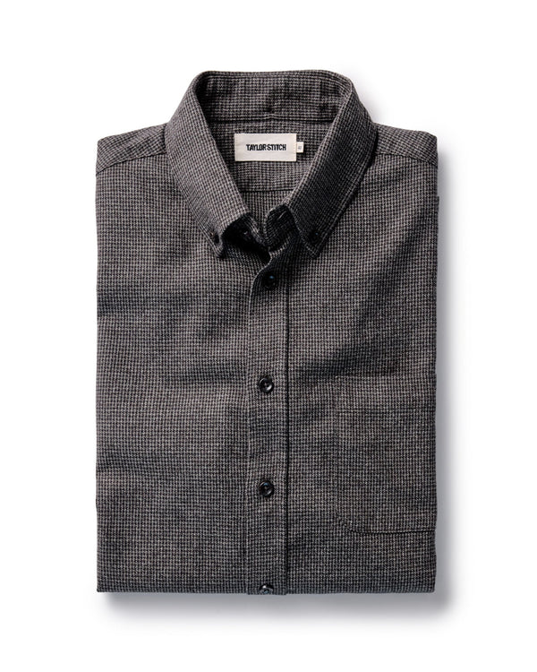 Folded dark green and gray checkered shirt with a brand label on a white background