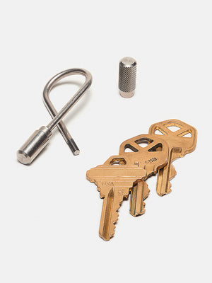 Set of brass keys and a keychain tool on a white background