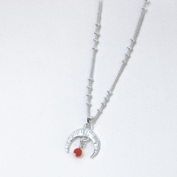 Silver necklace with a moon and red stone pendant on a white background