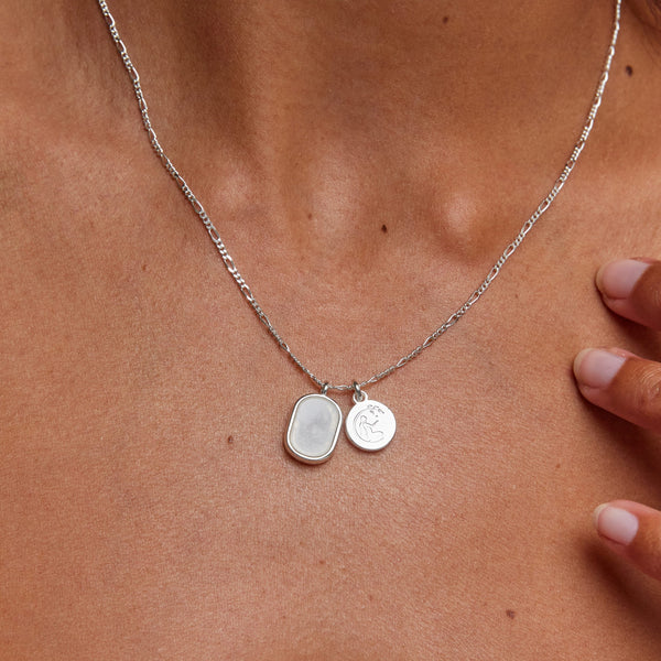 Silver necklace with two pendants on a person's neck