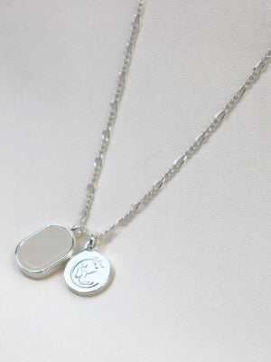 Silver necklace with two round pendants on a light gray background