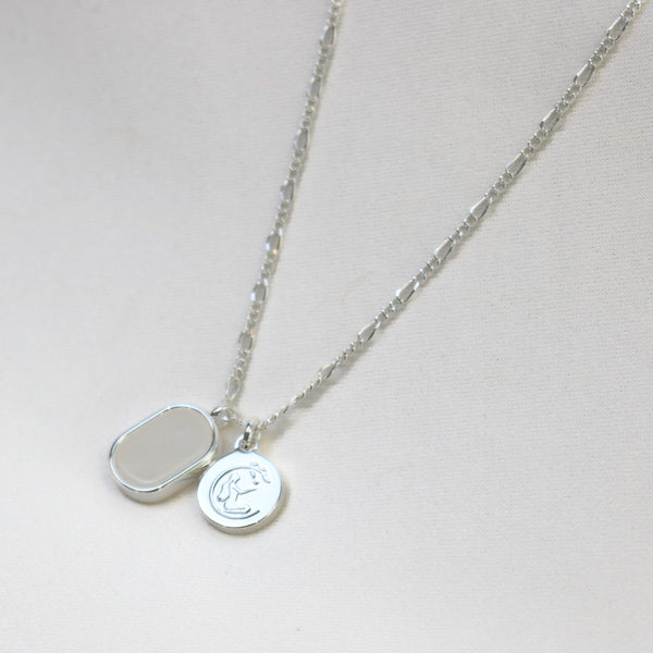 Silver necklace with two round pendants on a light gray background