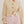 Woman wearing a beige cardigan and pink shorts on a plain background