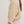 Woman wearing a beige sweater and pink skirt on a white background