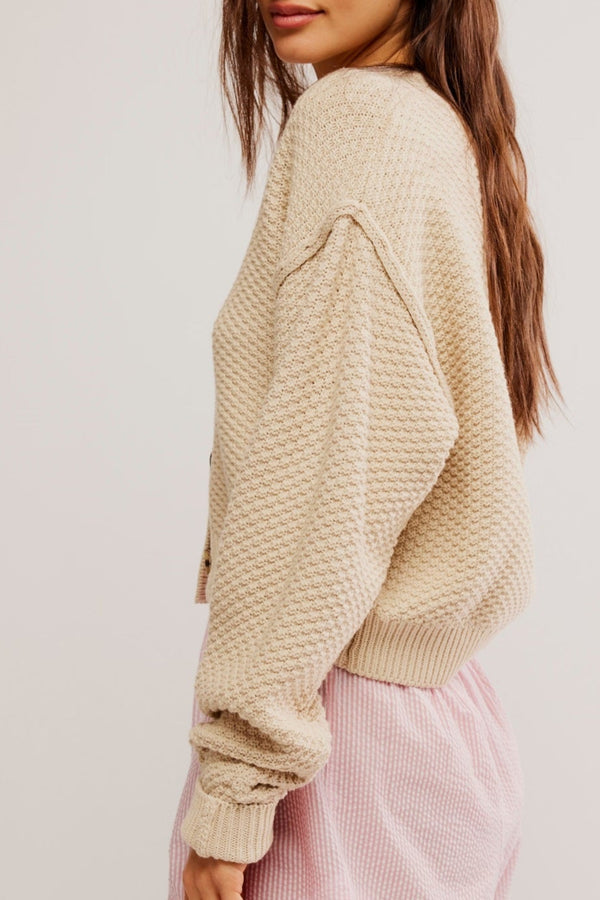 Woman wearing a beige sweater and pink skirt on a white background