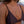 Close-up of a person wearing a brown bikini top with a necklace featuring a key pendant.