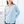 Woman wearing a light blue button-up shirt in a bright room.