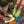 Person wearing colorful socks with avocado and heart patterns and yellow shoes on a wooden deck.