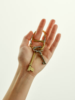 Hand holding a set of keys with a keychain against a light background