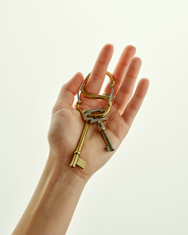 Hand holding a set of keys with a keychain against a light background