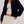 Woman wearing a navy cardigan over a white top and skirt on a plain background