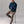 Man sitting on a stool wearing a blue sweater and brown pants against a plain background