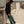 Man leaning against a wooden structure on a sandy beach.