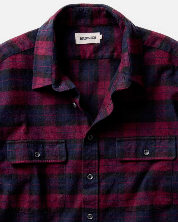 Red and black plaid shirt with a visible brand label on a white background