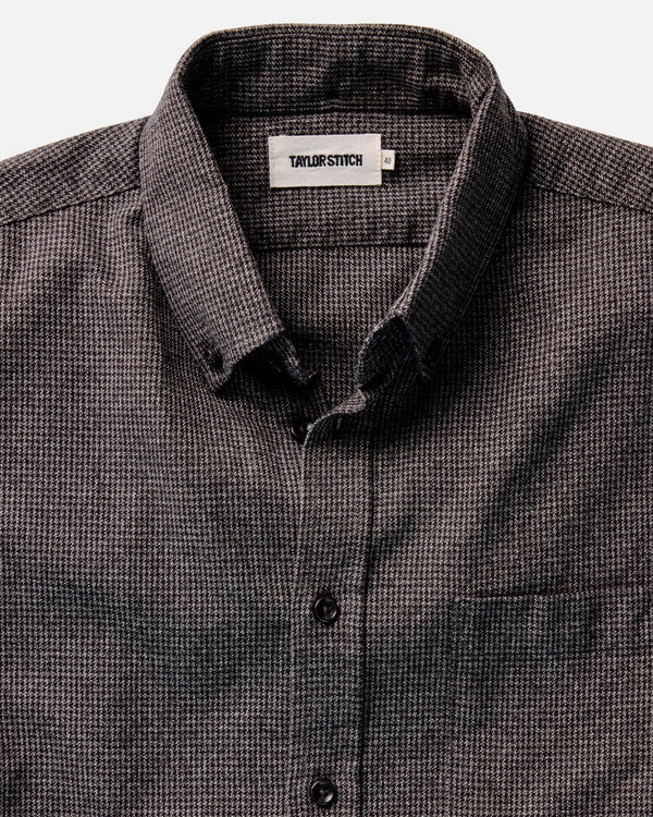 Close-up of a dark green and gray checkered shirt with 'Taylor Stitch' label on a white background
