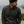 Man wearing a dark knit beanie and button-up shirt standing by a body of water.