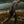 Man walking on a rocky shoreline with a lake and mountains in the background