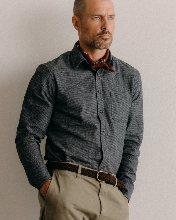 Man wearing a dark navy and gray patterned shirt with a red patterned collar against a plain background