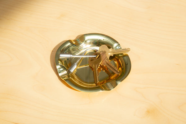 Gold dish with a key-shaped object on a wooden surface